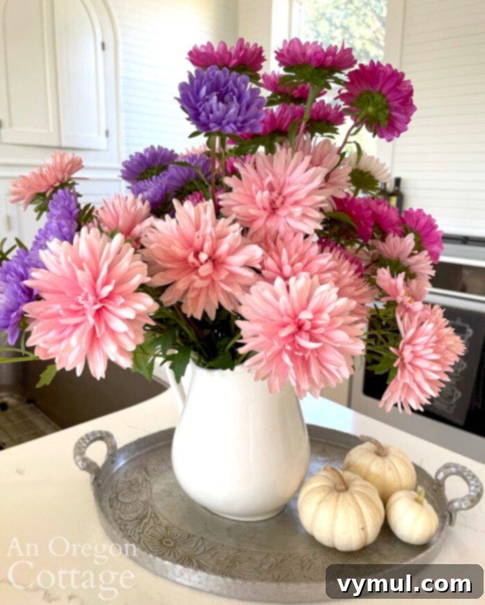 Fall Favorites: Cozy Decor, Fresh Blooms, Perfect Denim, Radiant Skin, & Essential Reads 5 A stunning bouquet of autumn giant asters, showcasing a vibrant mix of blush-pinks, purples, and whites, arranged beautifully in a rustic white pitcher. These long-lasting cut flowers, including varieties like 'Salmon Janina' and 'Giant Perfection Mix', bloom gloriously from August until the first frost, making them an ideal choice for vibrant, late-season fall arrangements.