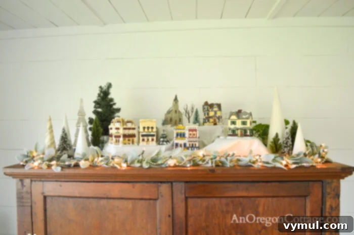 Christmas village display and tabletop trees on a TV cabinet in a farmhouse living room