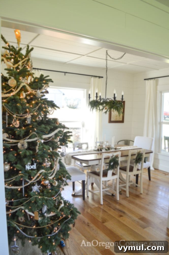 Farmhouse dining room decorated for Christmas with white, green, gold, and silver accents