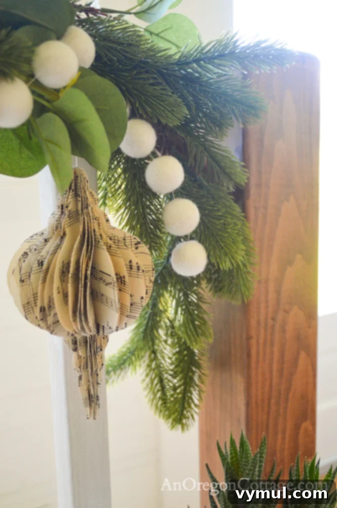 3D music sheet ornament hanging from a Christmas stair garland on a farmhouse bannister