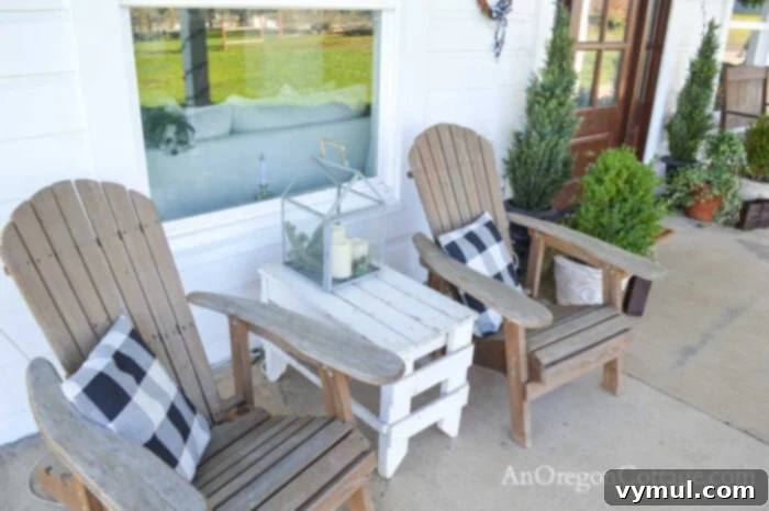 Adirondack chairs on farmhouse porch with buffalo check pillows and outdoor Christmas candles