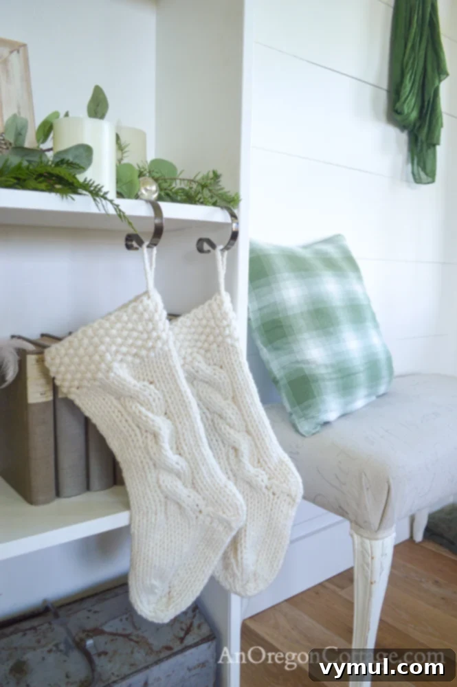 Hand-knitted cable white wool Christmas stockings on an entryway bookshelf