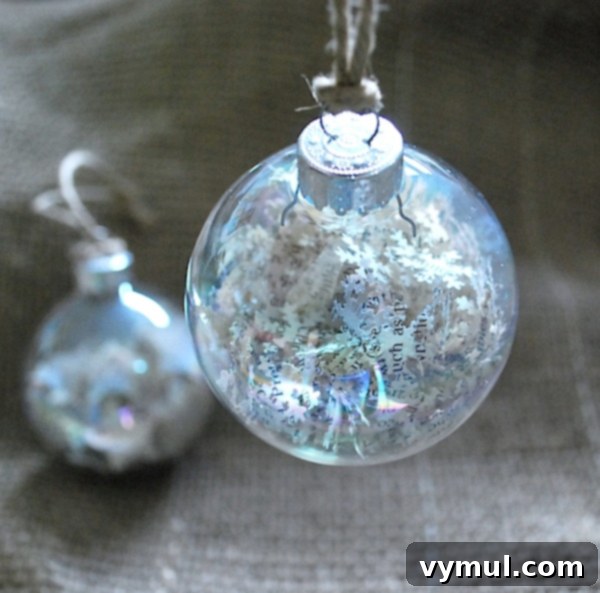 Close-up of a handmade book page snowflake punch ornament, showcasing the intricate detail of the paper cuts and how they fill the clear ball. A perfect vintage-style Christmas tree decoration.