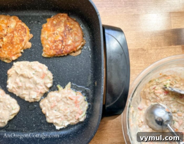 Speedy Sourdough Discard Veggie Fritters 7 Cooking sourdough vegetable fritters on a griddle with a scoop