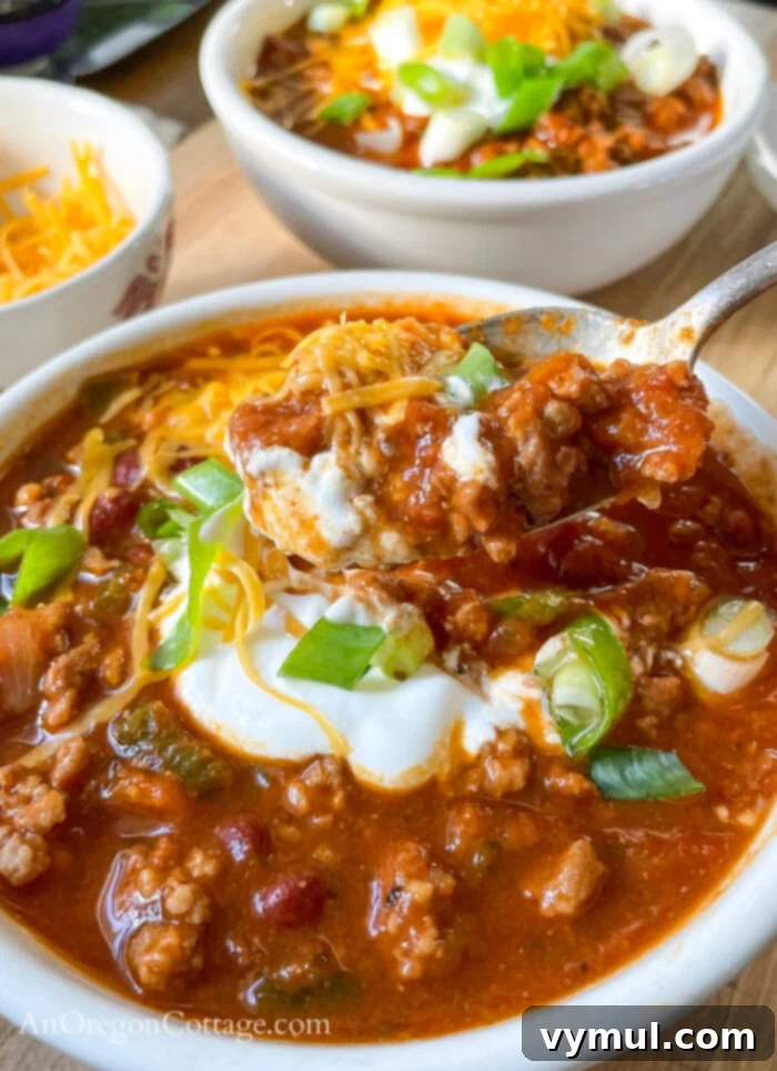 Effortless Chili For Any Cooker 8 eating chili with toppings on spoon