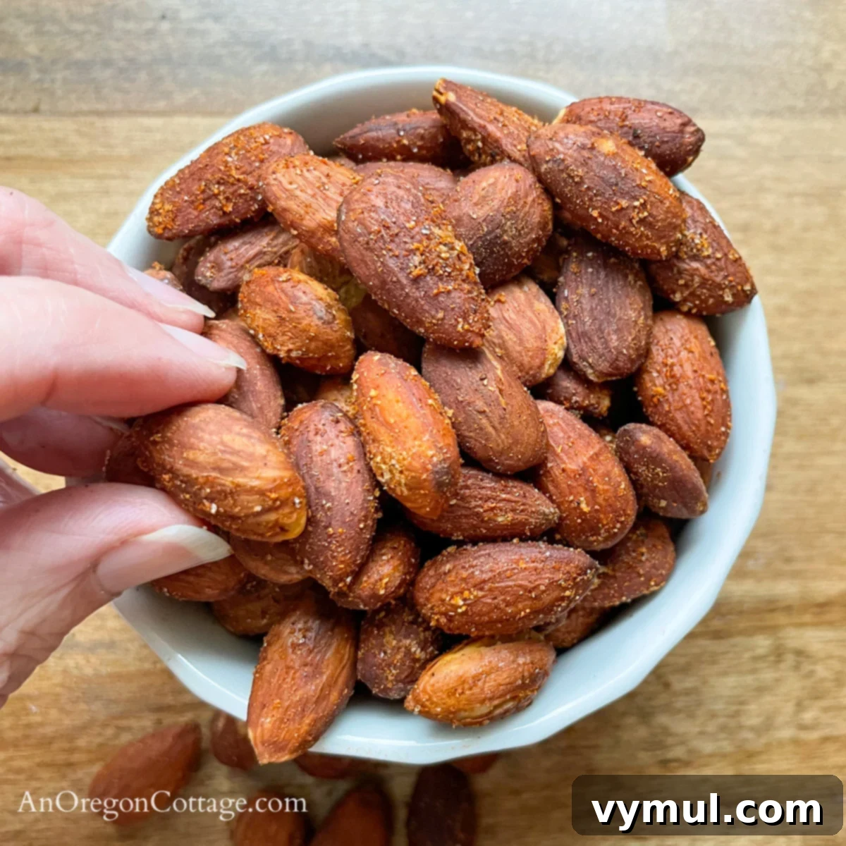 Chipotle Fire Almonds: Quick & Sugar-Free 8 hand reaching for chipotle spicy almonds from a bowl, showcasing their irresistible appeal