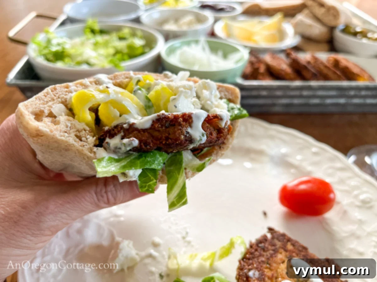A hand holding a filled Mediterranean tuna patty pita, ready to eat.
