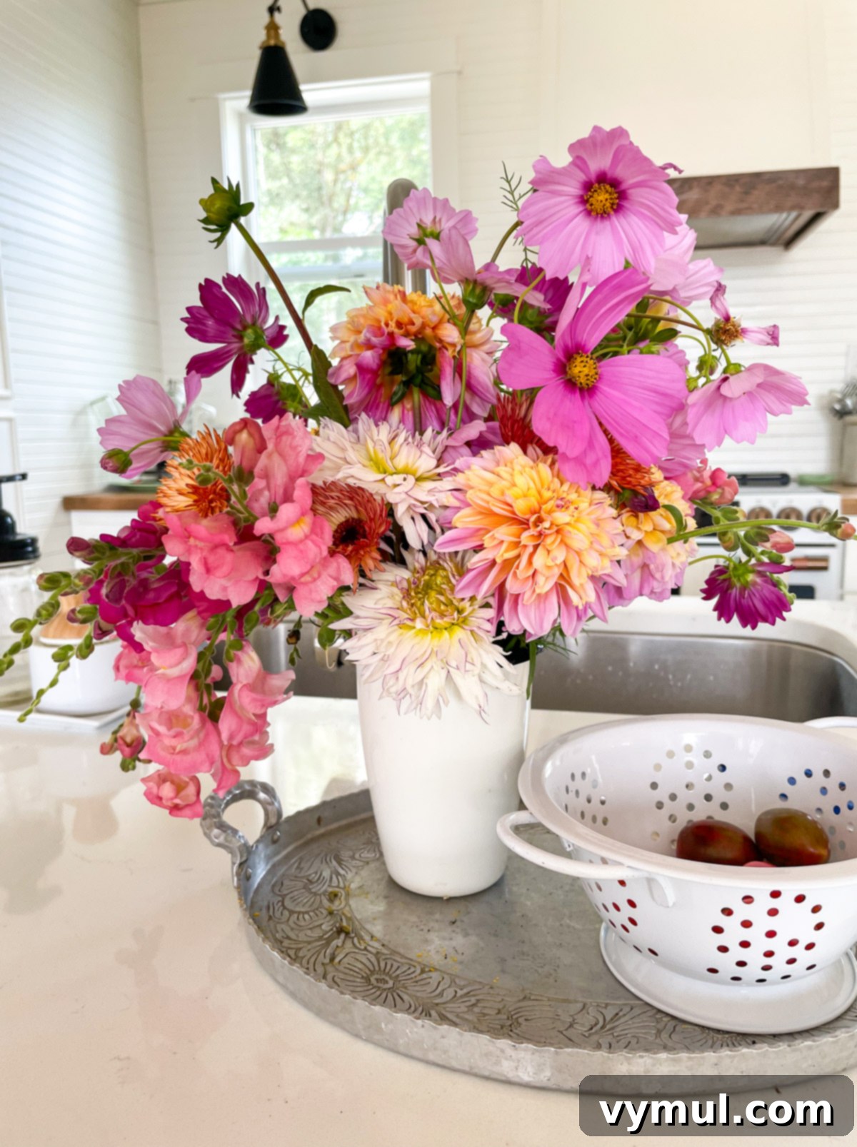 A charming vase filled with a vibrant arrangement of fresh-cut flowers sits on a white kitchen island.