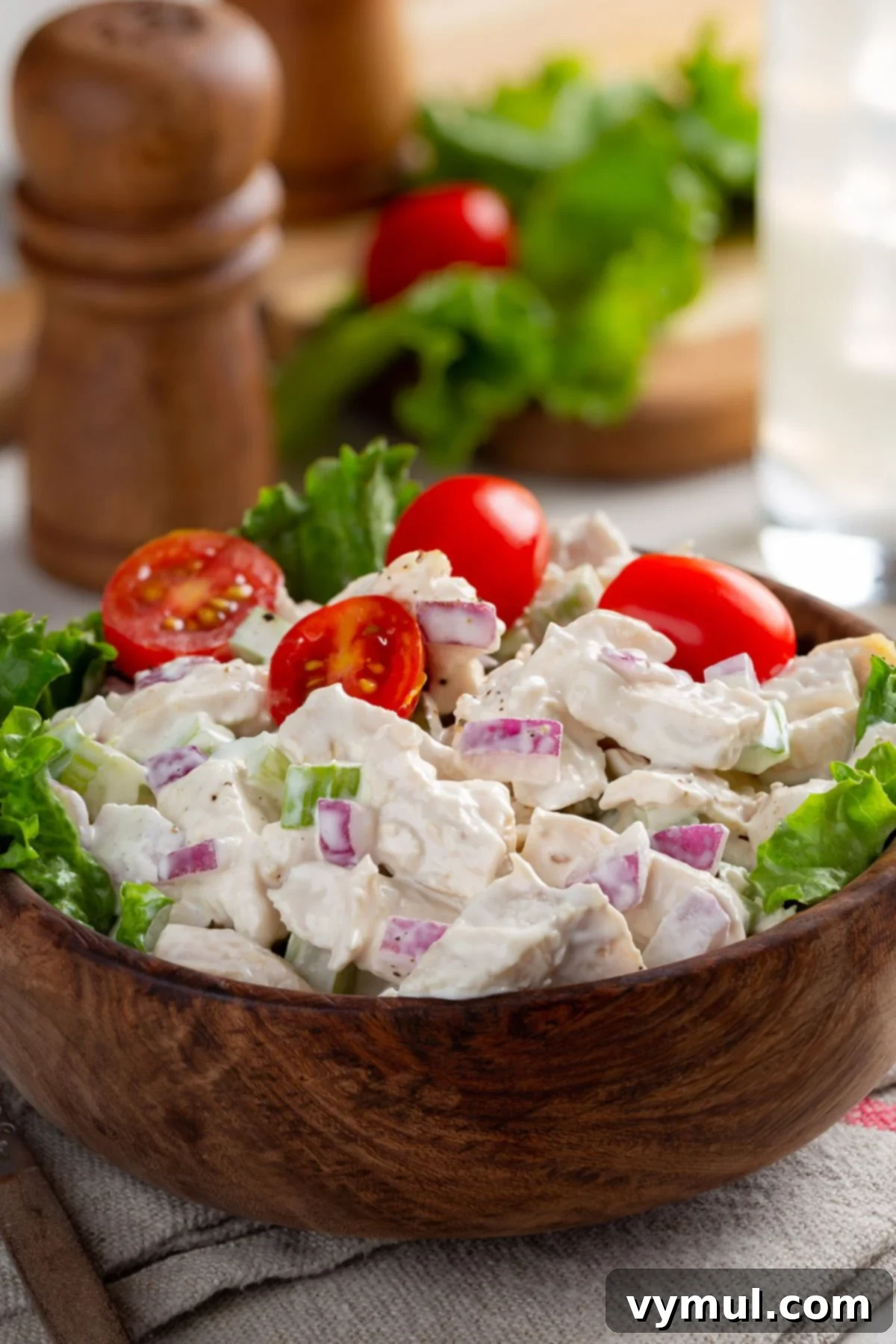 18 Foolproof Chicken Salad Recipes for Any Meal or Gathering 2 A vibrant chicken salad in a wooden bowl, garnished with fresh tomatoes and herbs, perfect for a healthy and delicious meal.