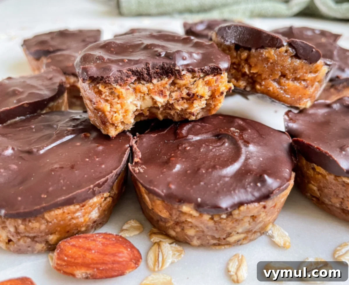 Several stacked mini no-bake chocolate almond oat cups, with one showcasing a perfect bite taken out, highlighting the layers.