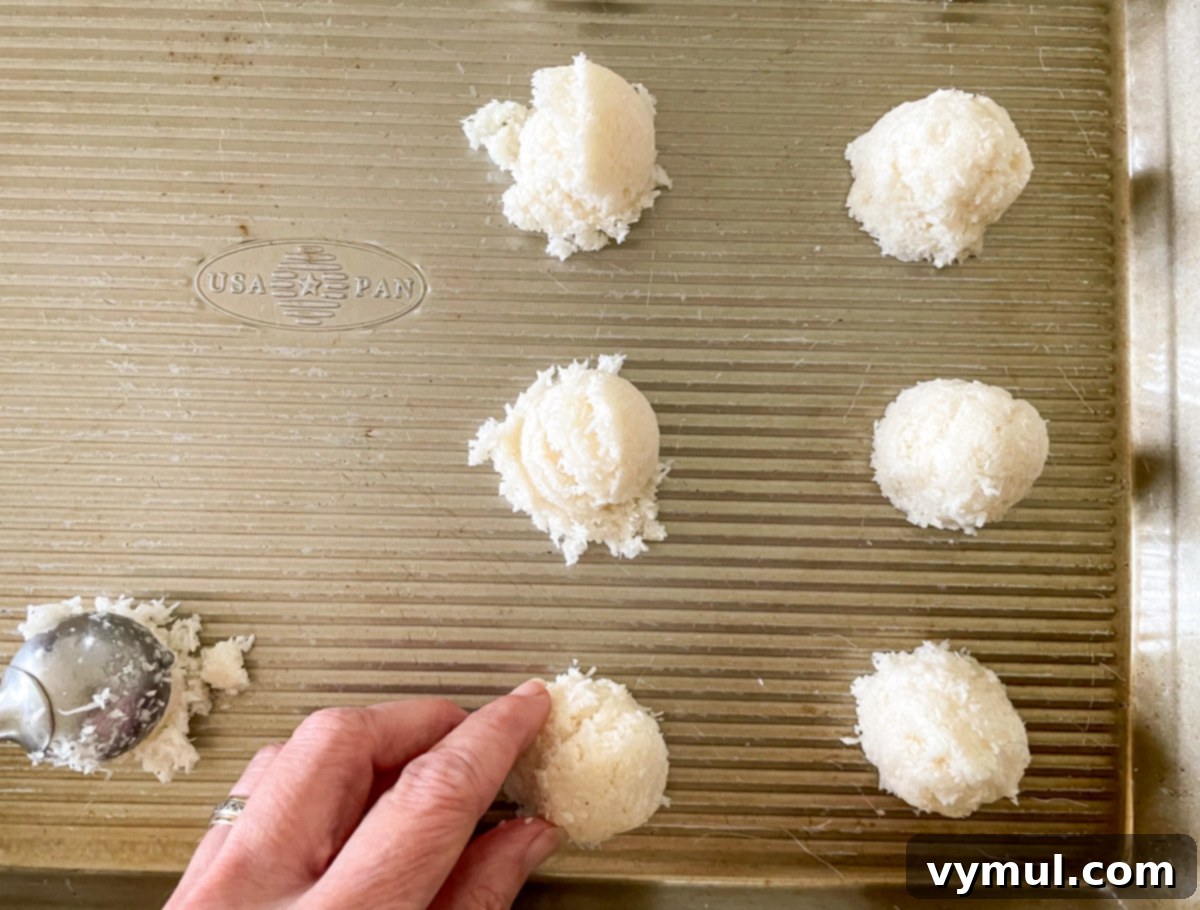 Effortless Coconut Macaroons No Flour No Condensed Milk 4 Shaping coconut macaroon dough into neat mounds on a prepared baking sheet, ensuring smooth edges for perfect cookies.