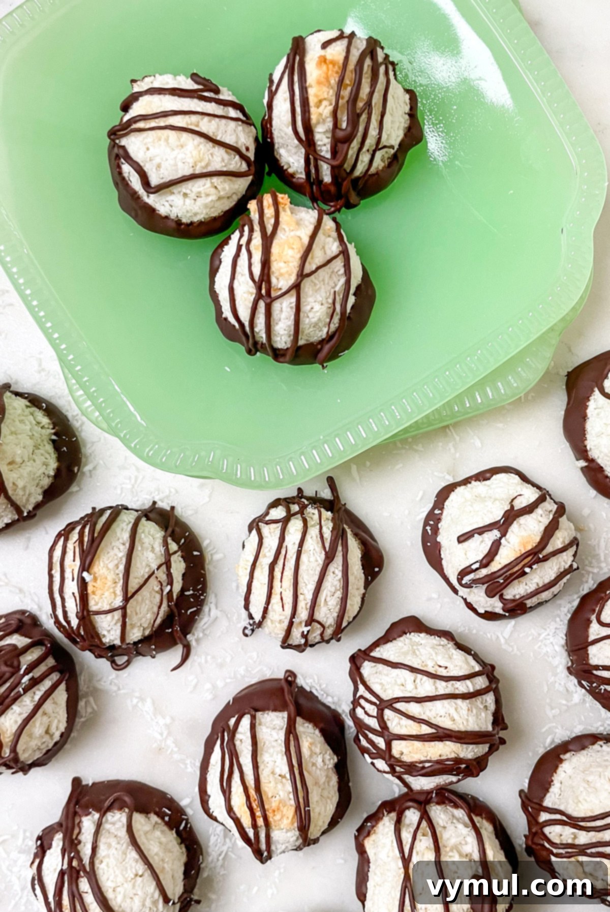 Effortless Coconut Macaroons No Flour No Condensed Milk 8 A beautifully composed shot from above of an assortment of chocolate-dipped and drizzled coconut macaroons arranged on green plates, ready for serving or gifting.
