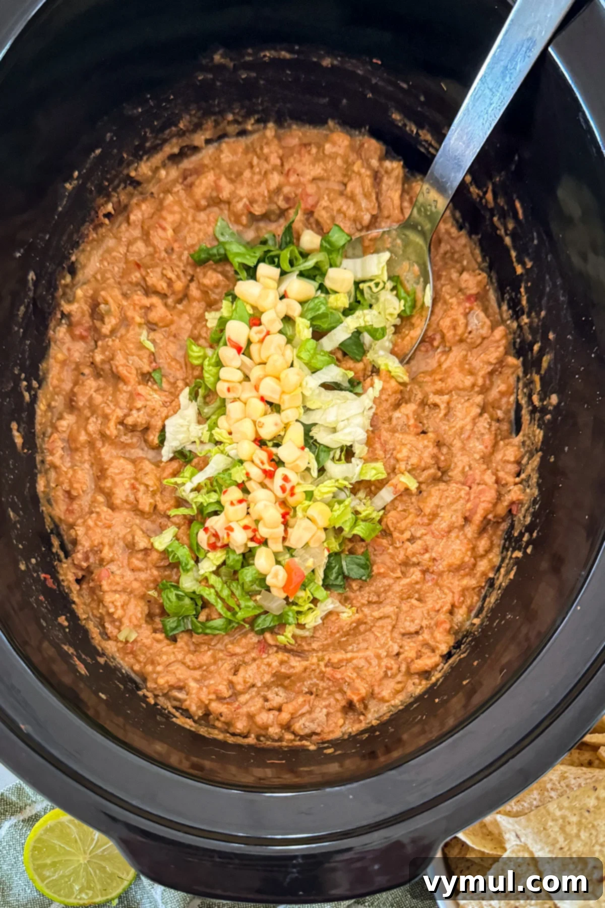 Hands-Off 5-Ingredient Taco Dip for Slow Cooker and Instant Pot 2 Taco dip with vibrant toppings served in a black slow cooker bowl, viewed from above, ready for a party.