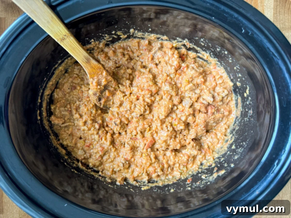 Hands-Off 5-Ingredient Taco Dip for Slow Cooker and Instant Pot 6 Stirring the cooked and melted taco dip in the slow cooker after it has finished cooking, showing a smooth, creamy texture.