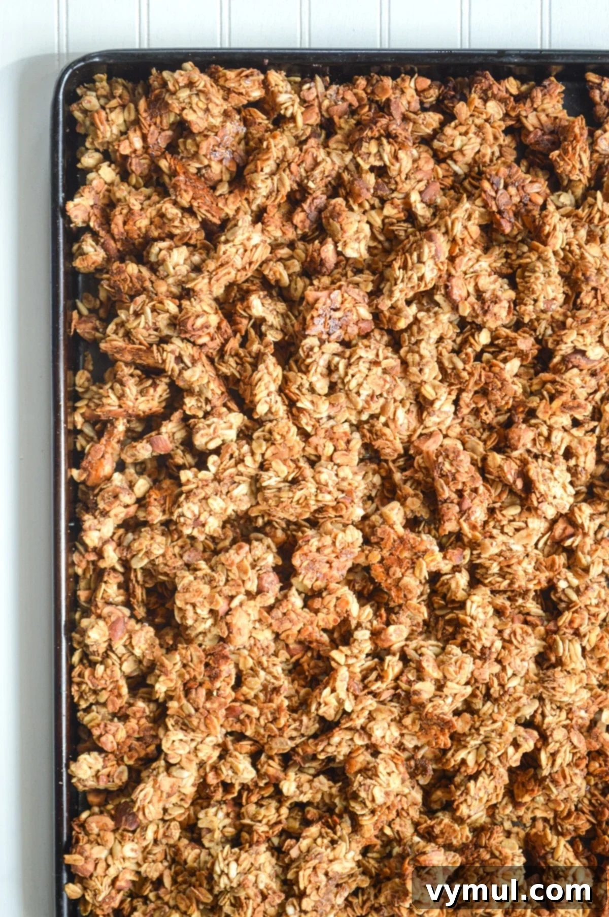 Healthy Quick Maple Honey Granola Bark Clusters 2 Freshly baked maple honey granola in a large baking pan, showcasing its golden-brown color and crunchy clusters.
