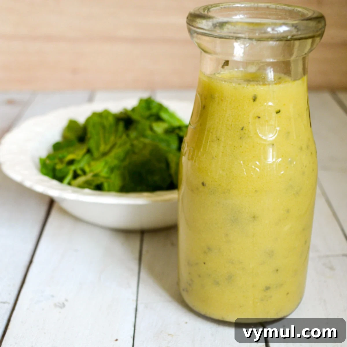 bottle of lemon vinaigrette dressing with bowl of salad