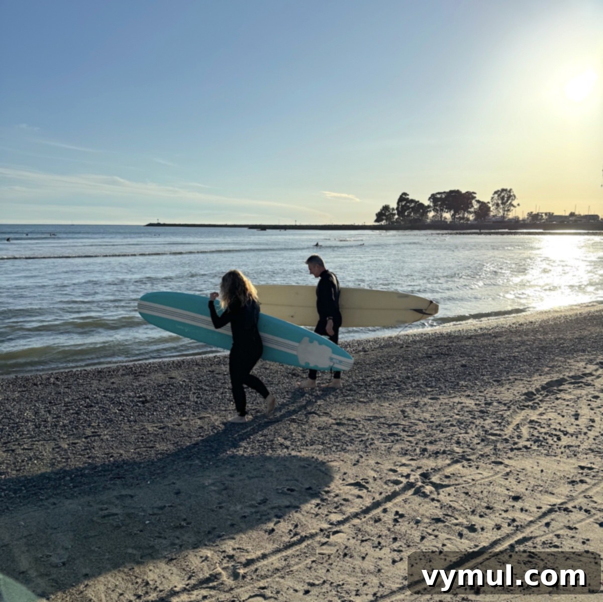A surfer walks towards the ocean with a surfboard, ready to catch waves in Southern California.