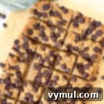 A small square of a peanut butter oatmeal bar on a white background, highlighting its golden crust and chocolate chips.