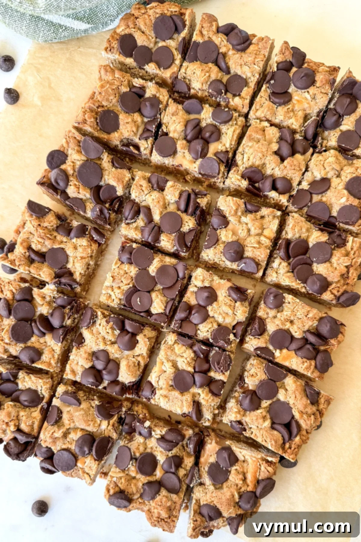Freshly baked peanut butter oatmeal bars, cut into squares and arranged on parchment paper, ready to be served.