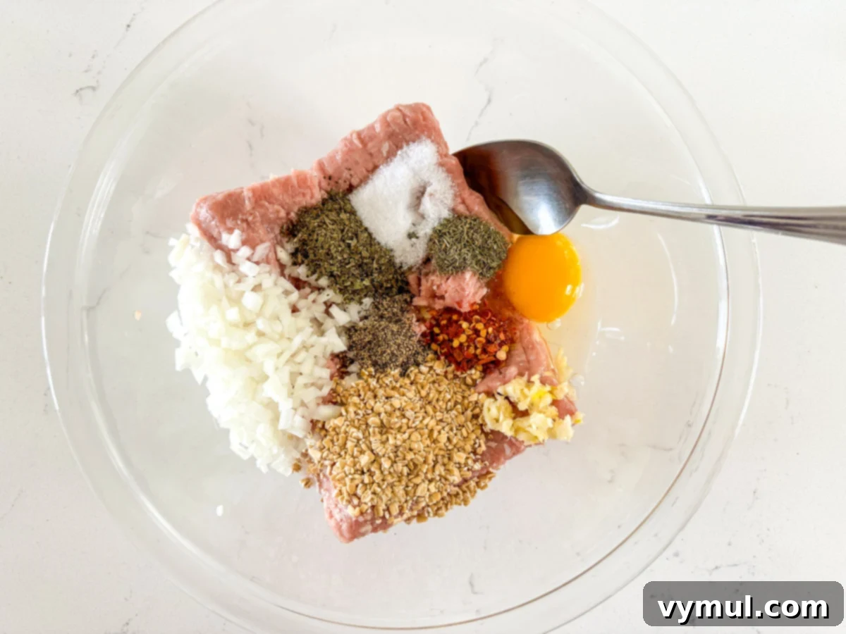 Speedy Wholesome Turkey Patties for Busy Mornings 4 Step-by-step image showing ground turkey, minced onion, garlic, and spices being mixed in a bowl for breakfast patties.