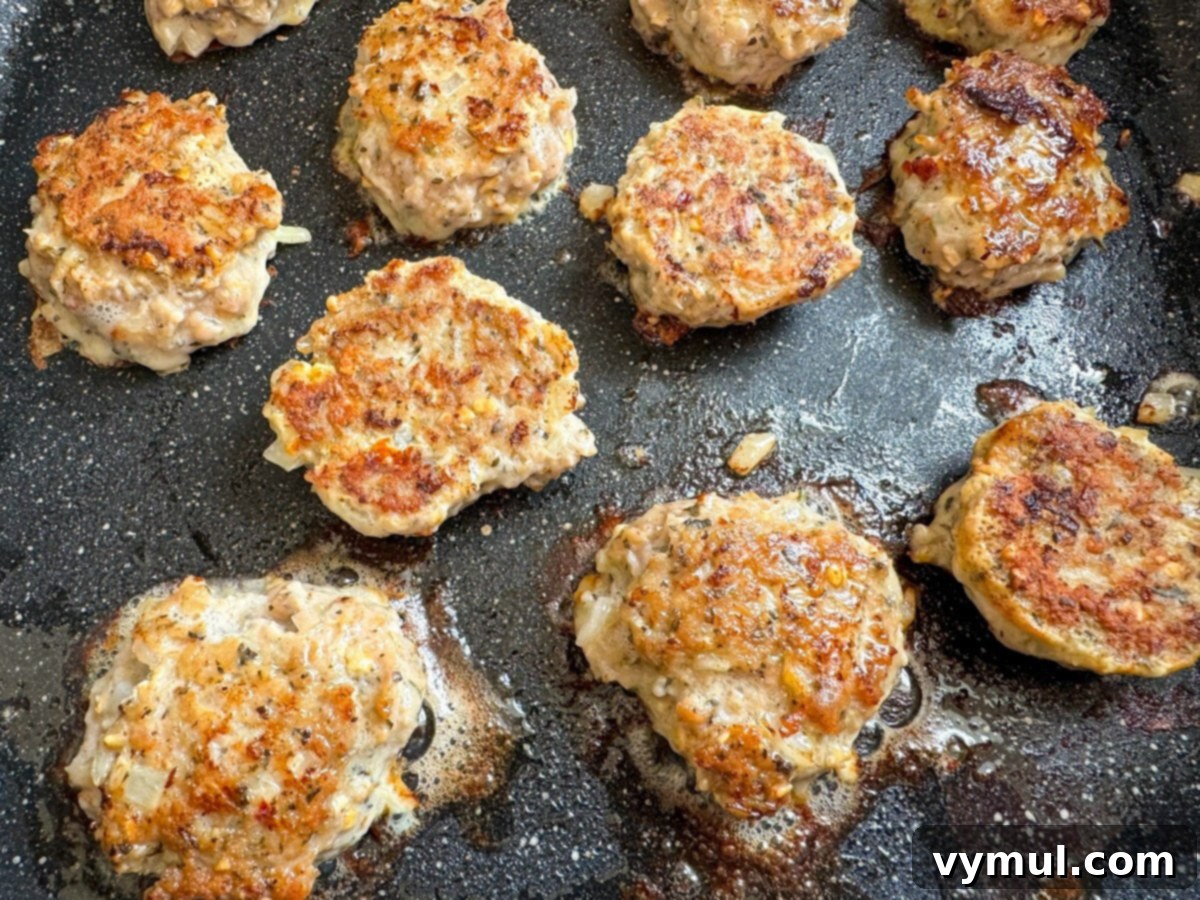 Speedy Wholesome Turkey Patties for Busy Mornings 6 Turkey patties browning and sizzling in a black skillet, indicating they are cooking through to perfection.
