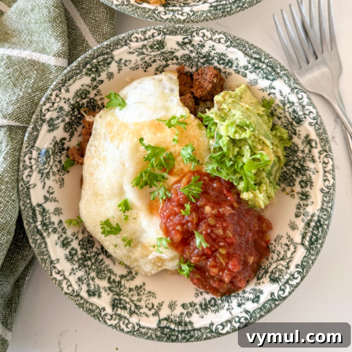 Speedy Six Ingredient High Protein Mexican Breakfast Bowls 6 A fully assembled Mexican breakfast bowl topped with fried egg, sliced avocado, and a dollop of red salsa.