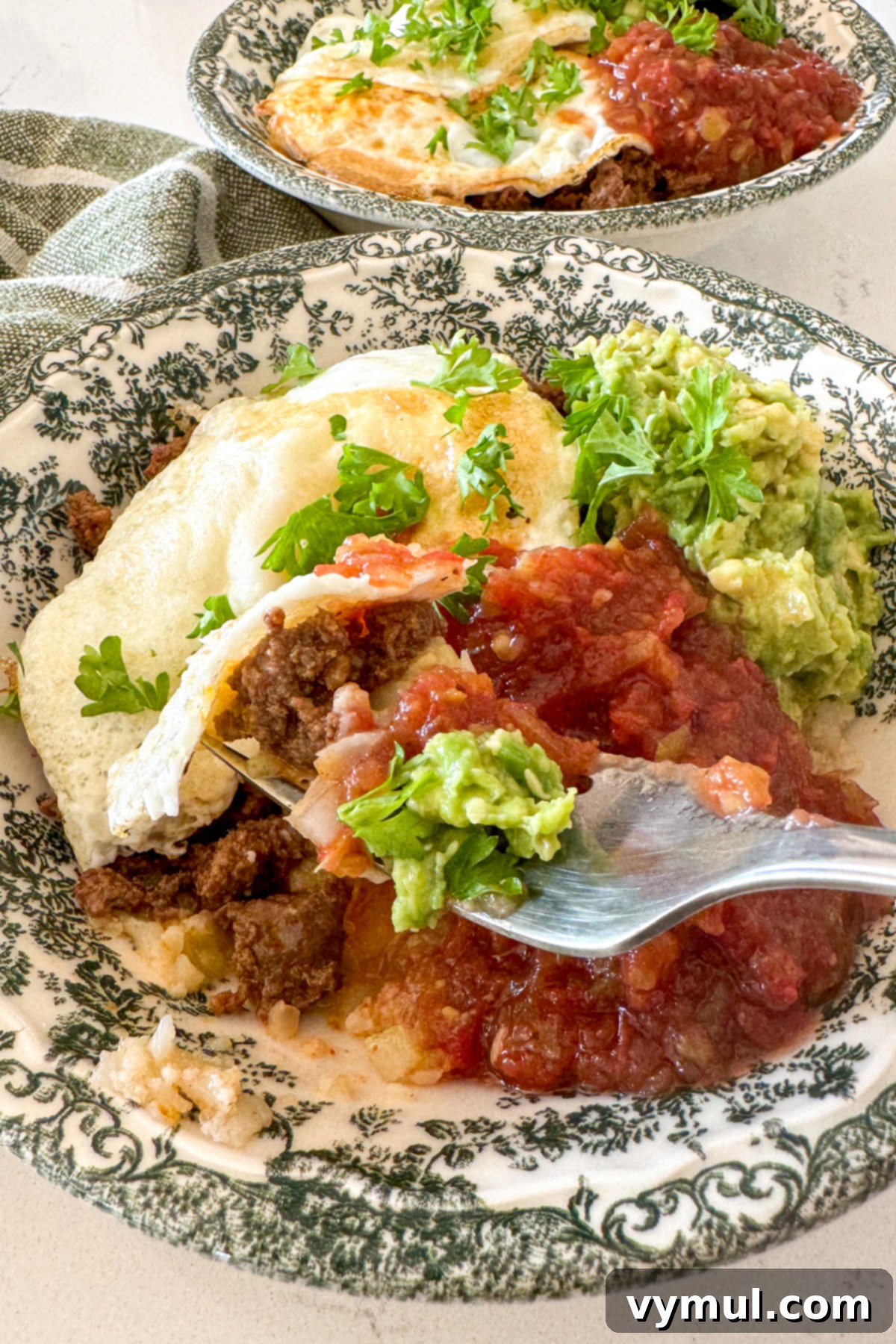 Speedy Six Ingredient High Protein Mexican Breakfast Bowls 7 A person enjoying a Mexican breakfast bowl, holding a fork, showing the vibrant ingredients.