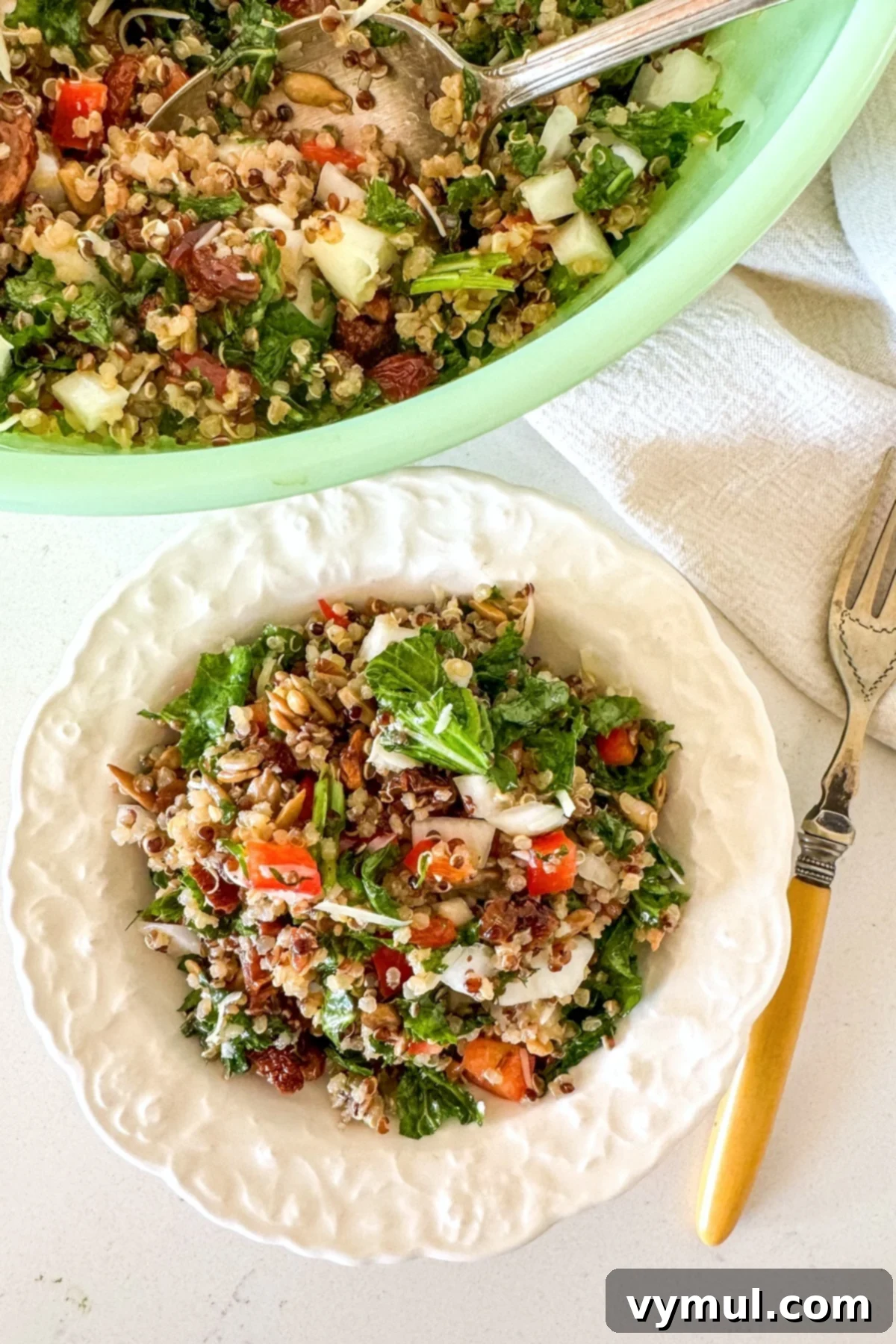 Zesty Lemon and Parmesan Kale Quinoa Salad 2 Freshly prepared kale quinoa salad served in a small white bowl, garnished with a sprinkle of cheese.