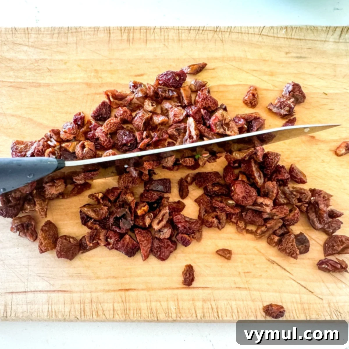 Zesty Lemon and Parmesan Kale Quinoa Salad 6 Hands chopping dried cherries on a cutting board.