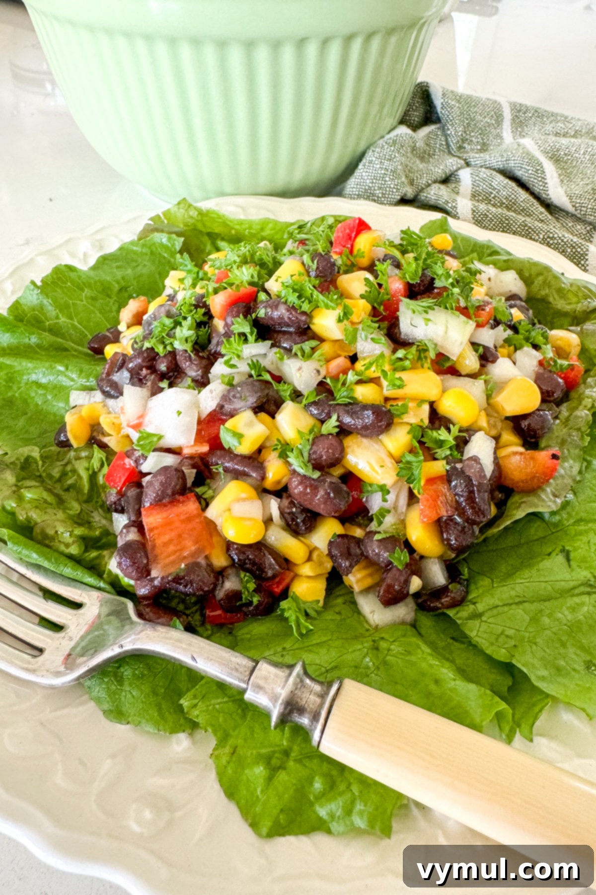 Zesty 10 Minute Black Bean and Corn Salad 6 black bean salad with corn on a bed of lettuce on white plate