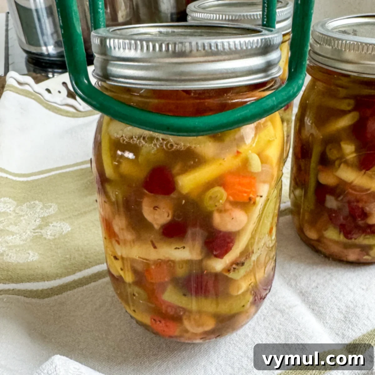 Removing hot, freshly canned jars of three bean salad from a water bath canner after processing.