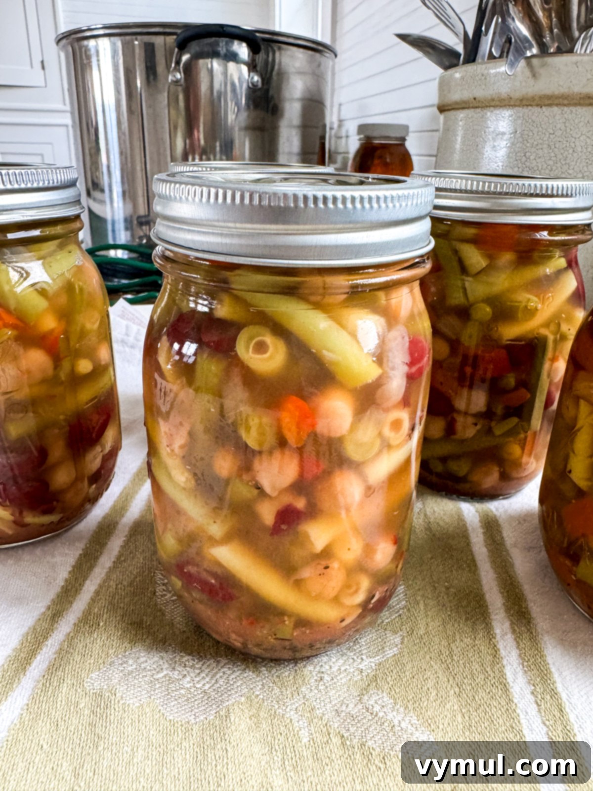 Cooling jars of freshly water bath canned three bean salad on a towel-lined tray to check seals.