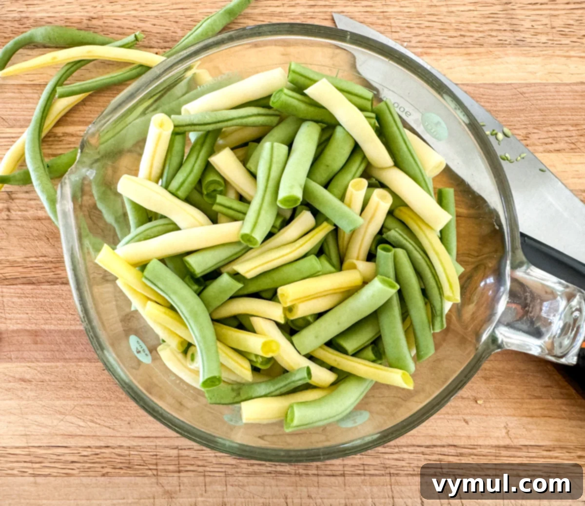 Prepping fresh green beans by cutting them into bite-sized pieces for the three bean salad recipe.
