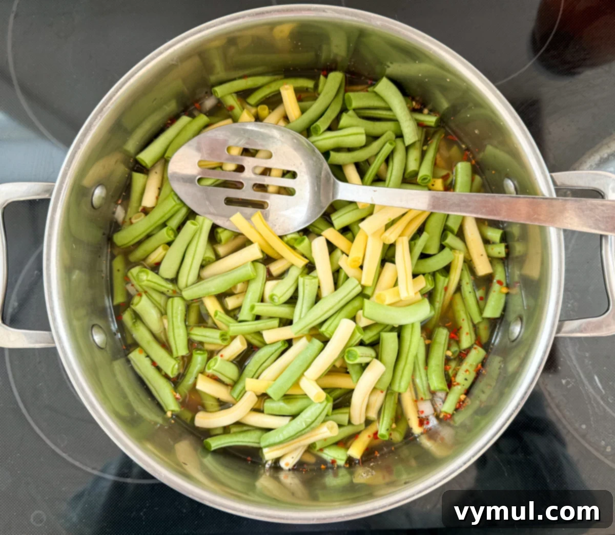 All three bean salad ingredients, including beans, chopped vegetables, and liquids, combined in a large stockpot ready for cooking.