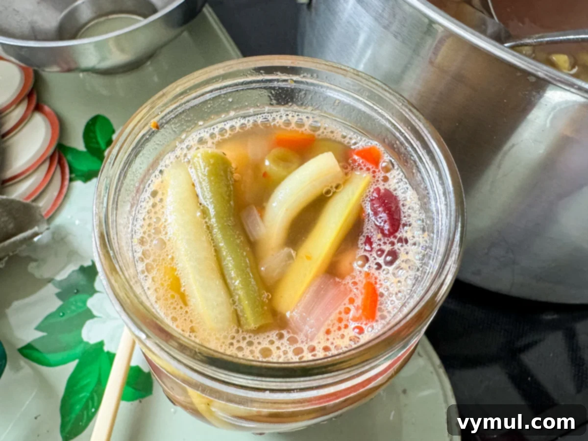 A canning jar filled with three bean salad and brine, showing the correct 1/2 inch headspace before sealing.