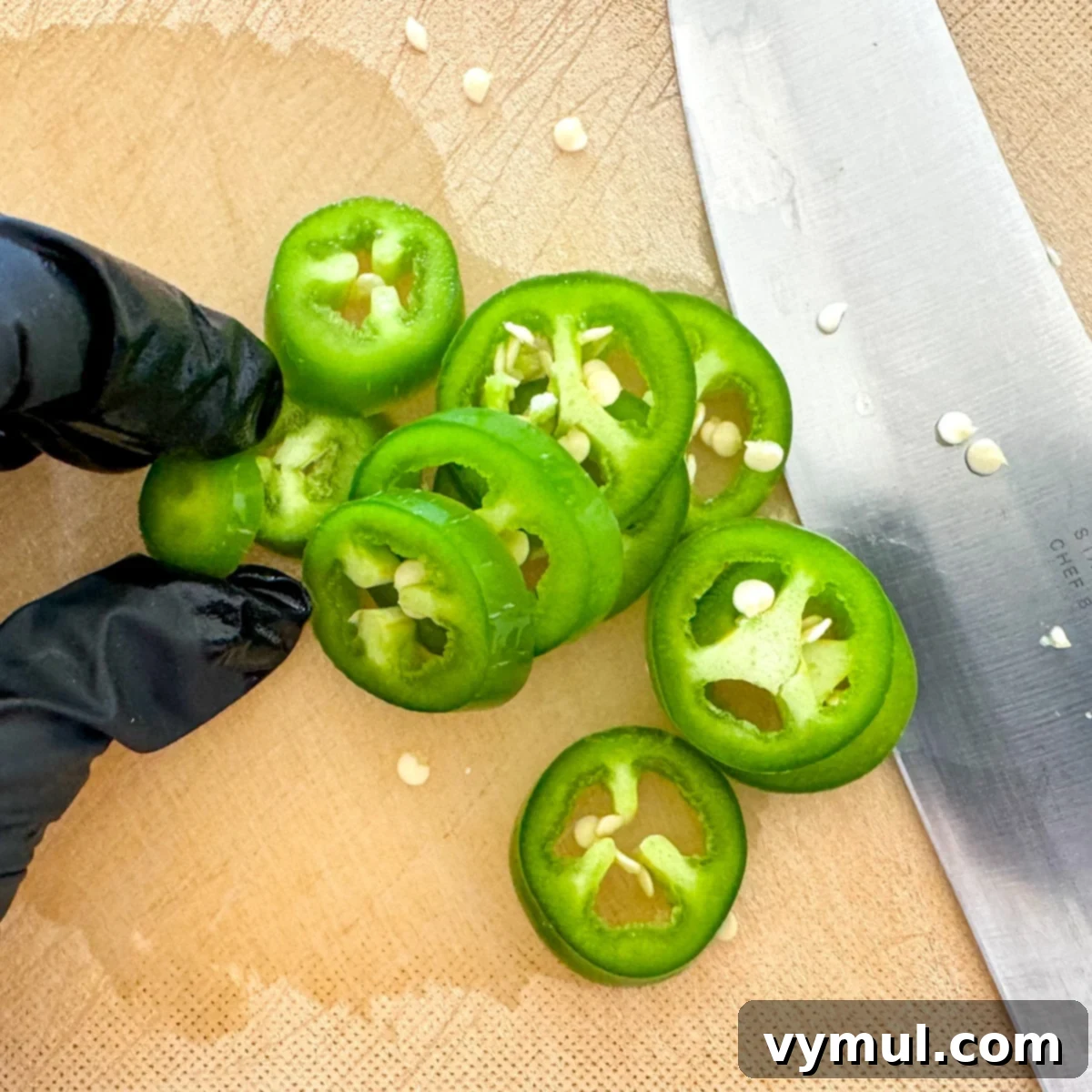 Sweet and Spicy Lower Sugar Cowboy Candy for Easy Canning 4 slicing jalapeños with a glove