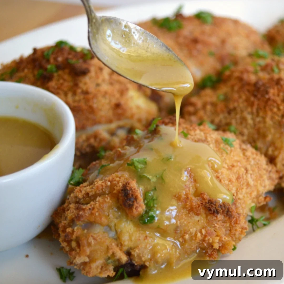 pouring sauce over baked maple mustard chicken
