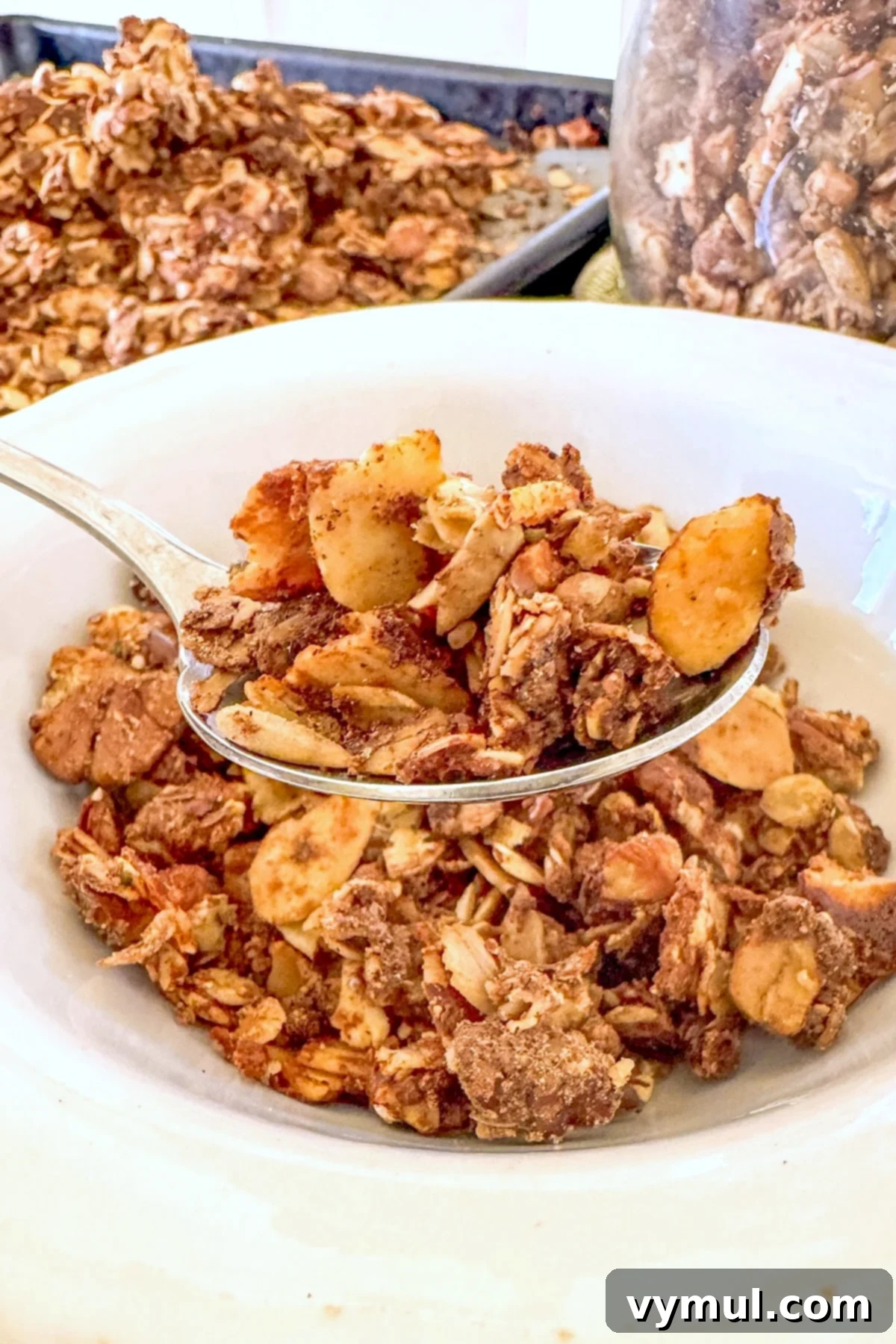 A serving of high-protein maple cinnamon granola in a white bowl, topped with fresh berries and chia seeds, highlighting a healthy breakfast.