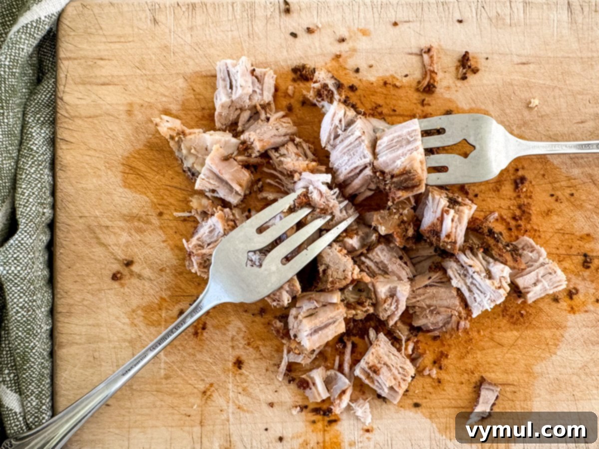 shredding pork sirloin on cutting board
