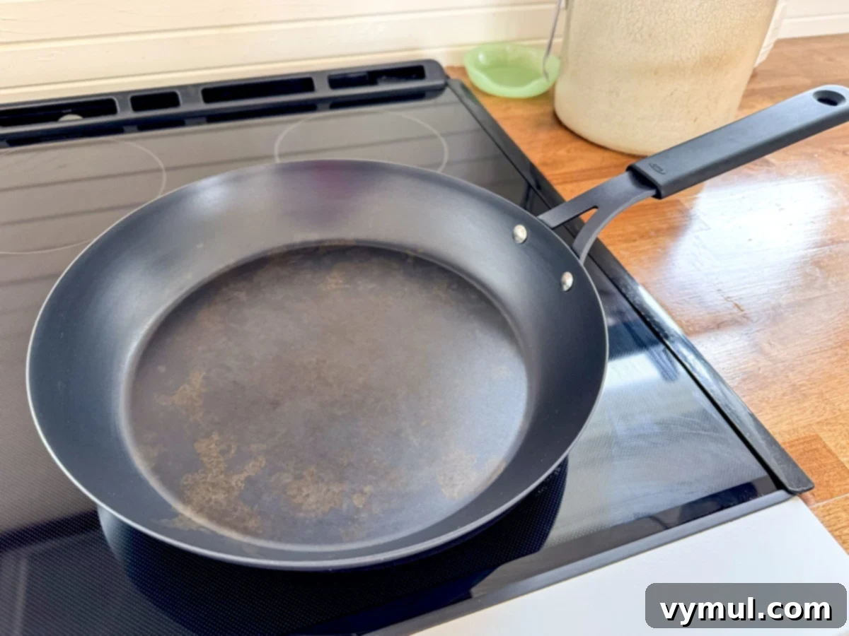 83 Good Things: Spring Garden, Favorite Skillet, Berry Patch, and New Reads 5 Pre-seasoned carbon steel skillet on a stovetop, showing its characteristic dark, rich patina.