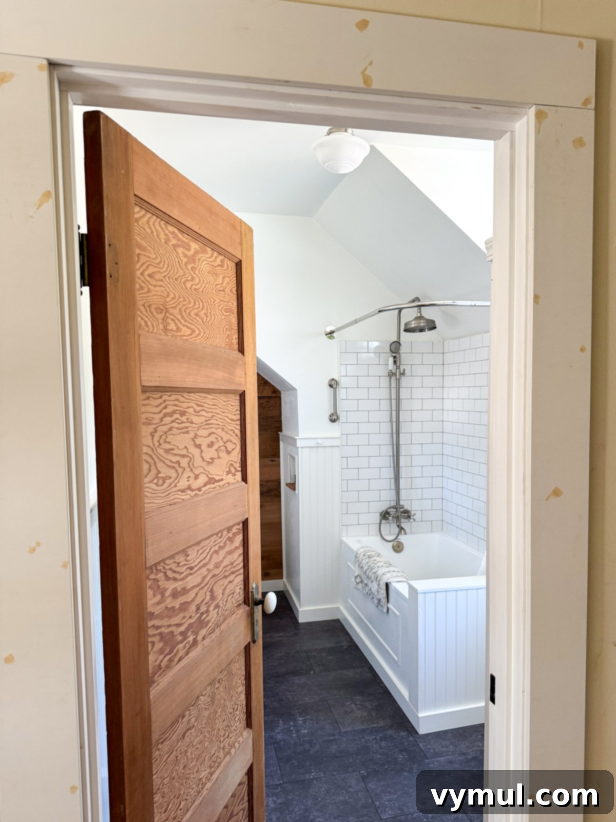 Remodeled farmhouse bathroom entrance, showcasing vintage wood door and period details.