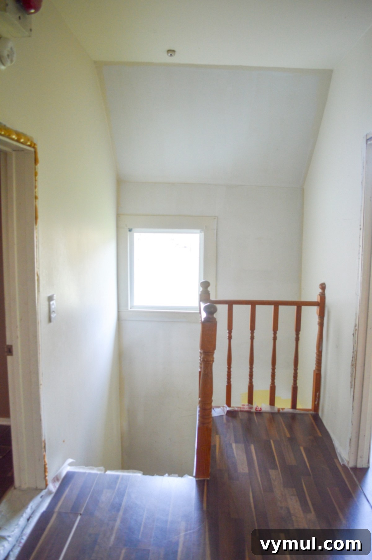 Dilapidated stairwell before any renovation, with a noticeable fire bell.