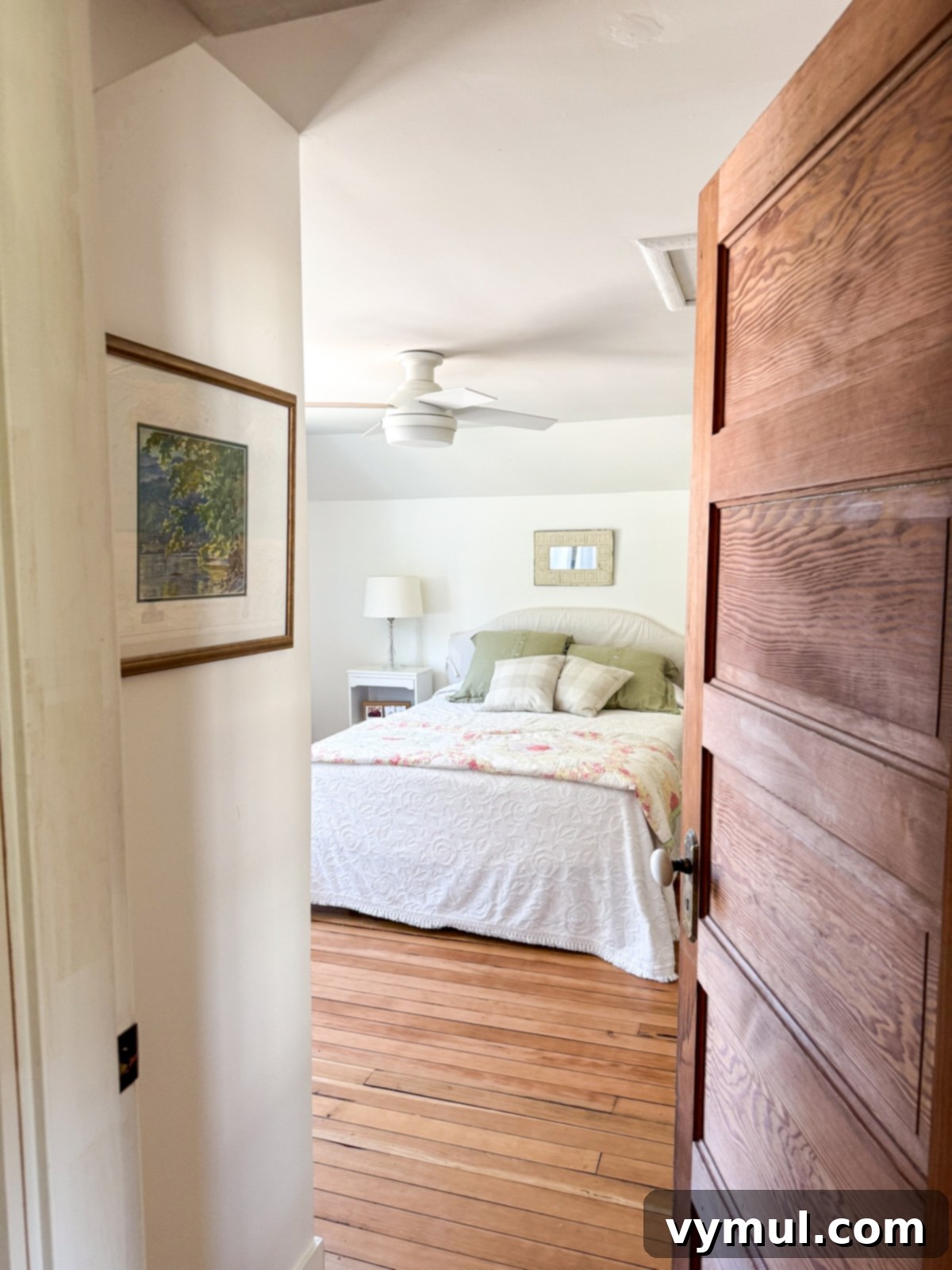 Inviting farmhouse guest room viewed through a vintage wooden door, showcasing its character.