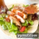 spooning tomato vinaigrette onto a salad