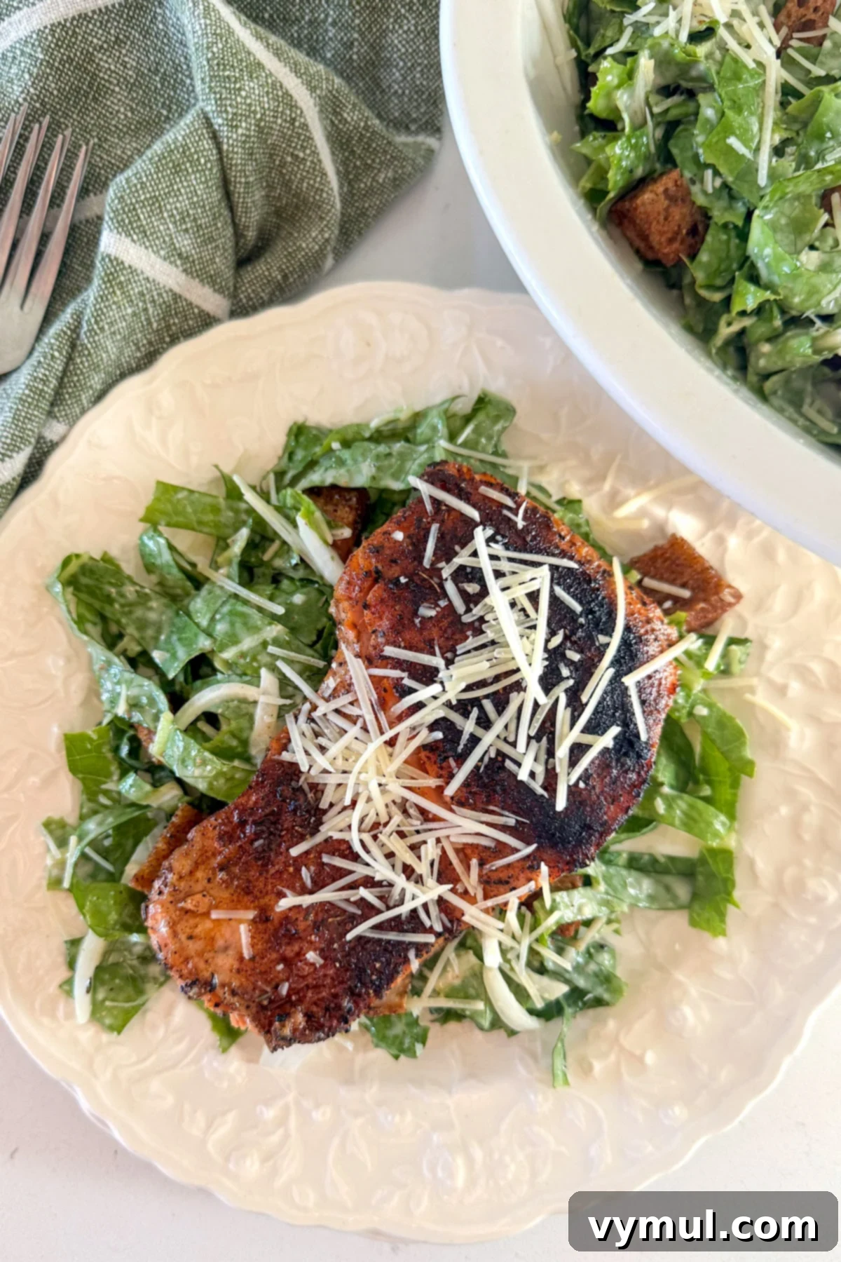 Perfect Pan-Seared Salmon Caesar 2 Freshly prepared Caesar salmon salad on a white plate, showcasing crispy croutons, tender salmon, and romaine lettuce.