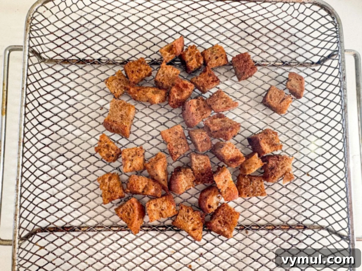 Perfect Pan-Seared Salmon Caesar 4 Homemade croutons cooking in an air fryer basket, golden brown and crispy.