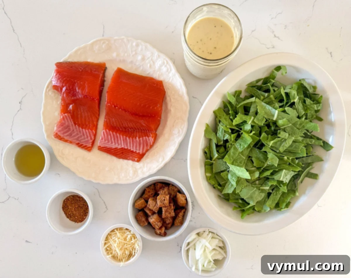 Perfect Pan-Seared Salmon Caesar 5 Ingredients for salmon Caesar salad laid out: salmon fillets, romaine lettuce, parmesan cheese, sweet onion, and a bowl of Caesar dressing.