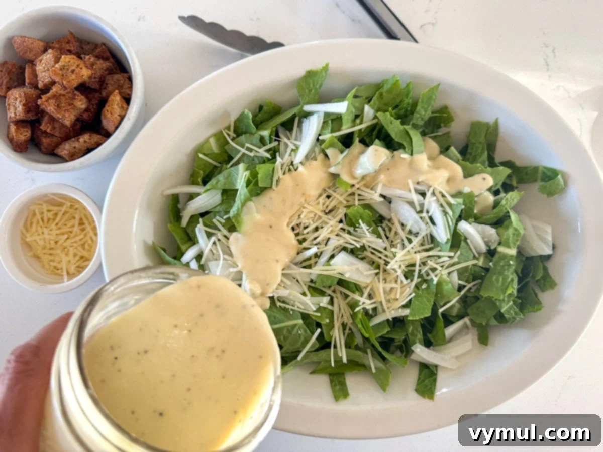 Perfect Pan-Seared Salmon Caesar 6 Chopped romaine lettuce, sweet onion, and parmesan cheese in a bowl, drizzled with Caesar dressing and being tossed.