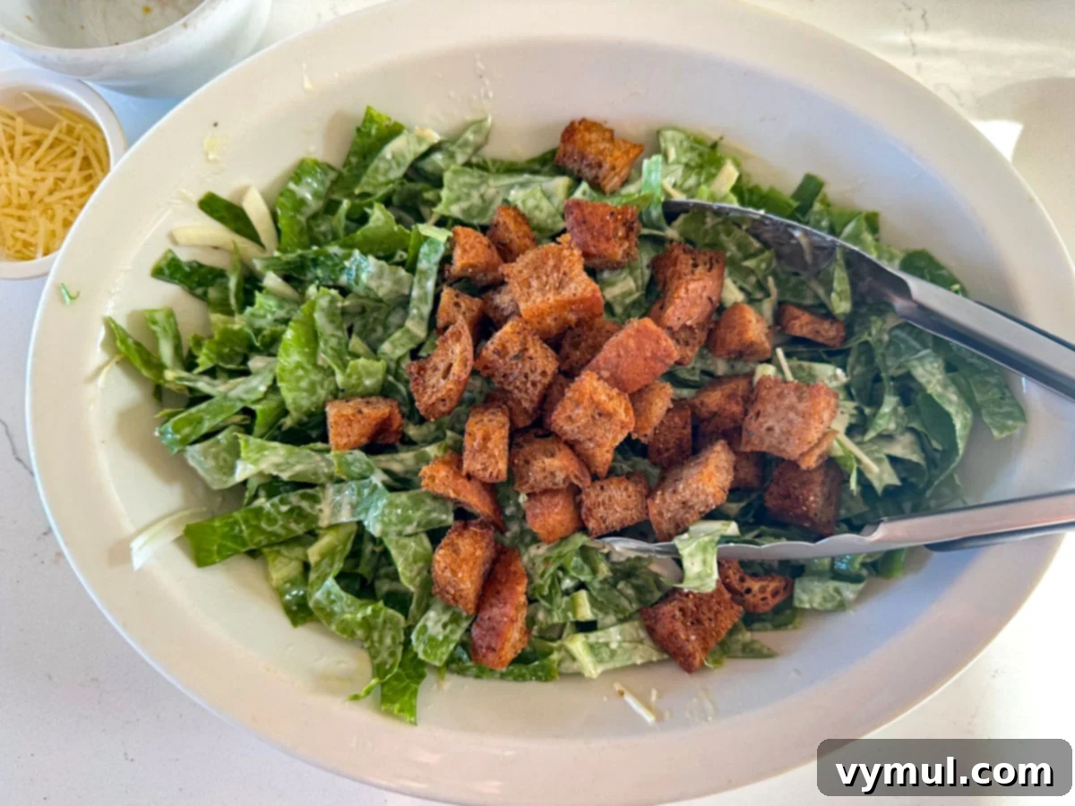 Perfect Pan-Seared Salmon Caesar 7 Adding golden, crispy homemade croutons to a bowl of dressed Caesar salad.