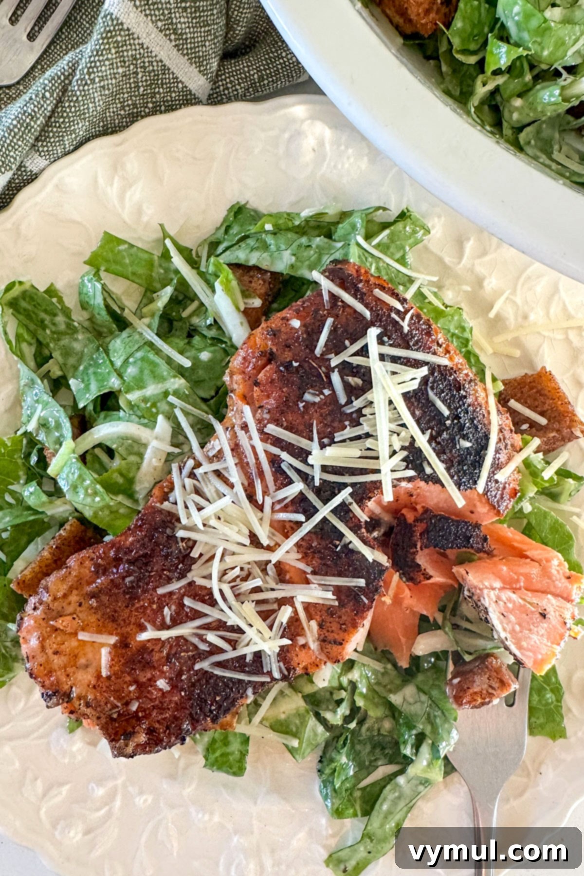 Perfect Pan-Seared Salmon Caesar 10 A close-up of a fork taking a bite of salmon Caesar salad, showing the crispy skin and fresh greens.
